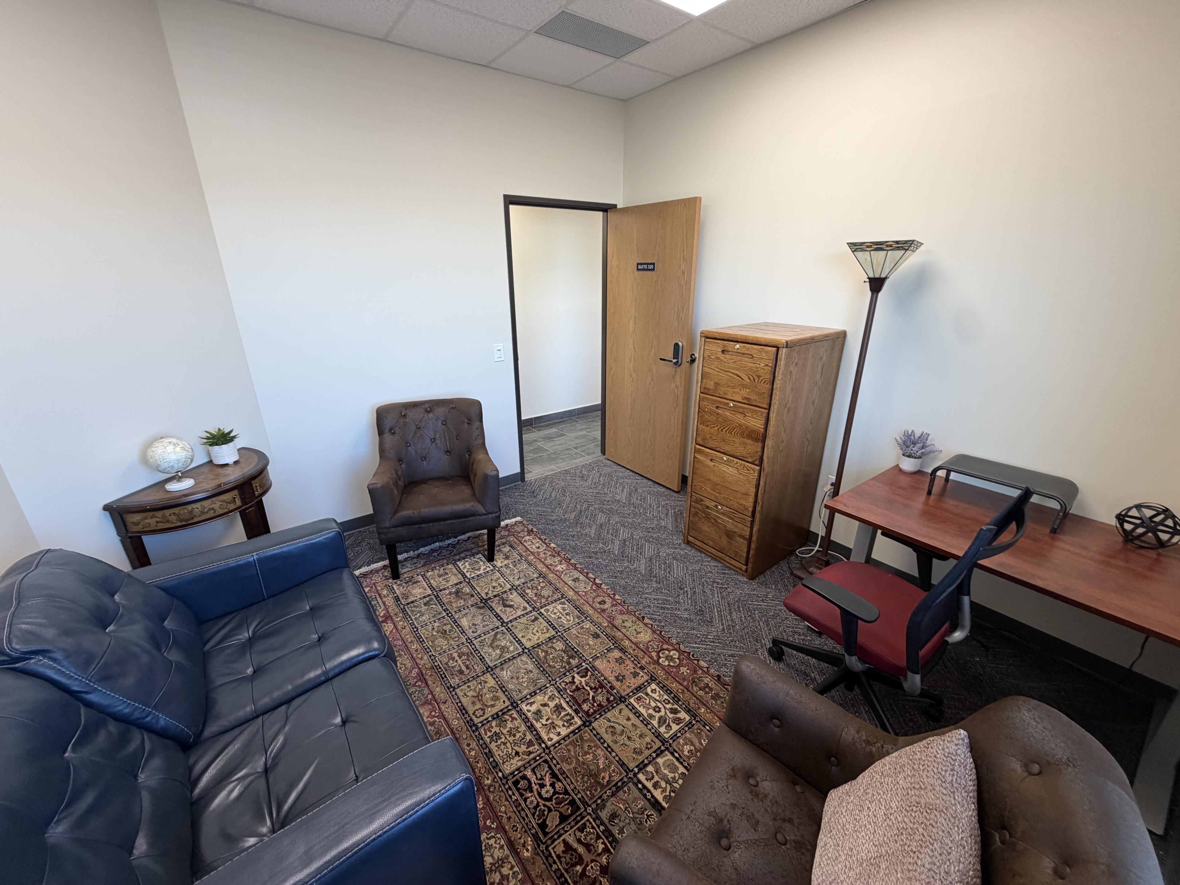 Suite 310 — blue leather sofa, lounge chair, lamp, and desk in the corner
