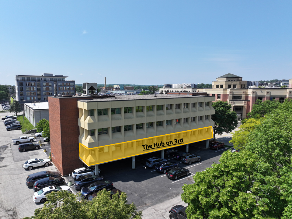 Aerial view of The Hub on 3rd, a four-story building in downtown Rochester, with the city skyline behind