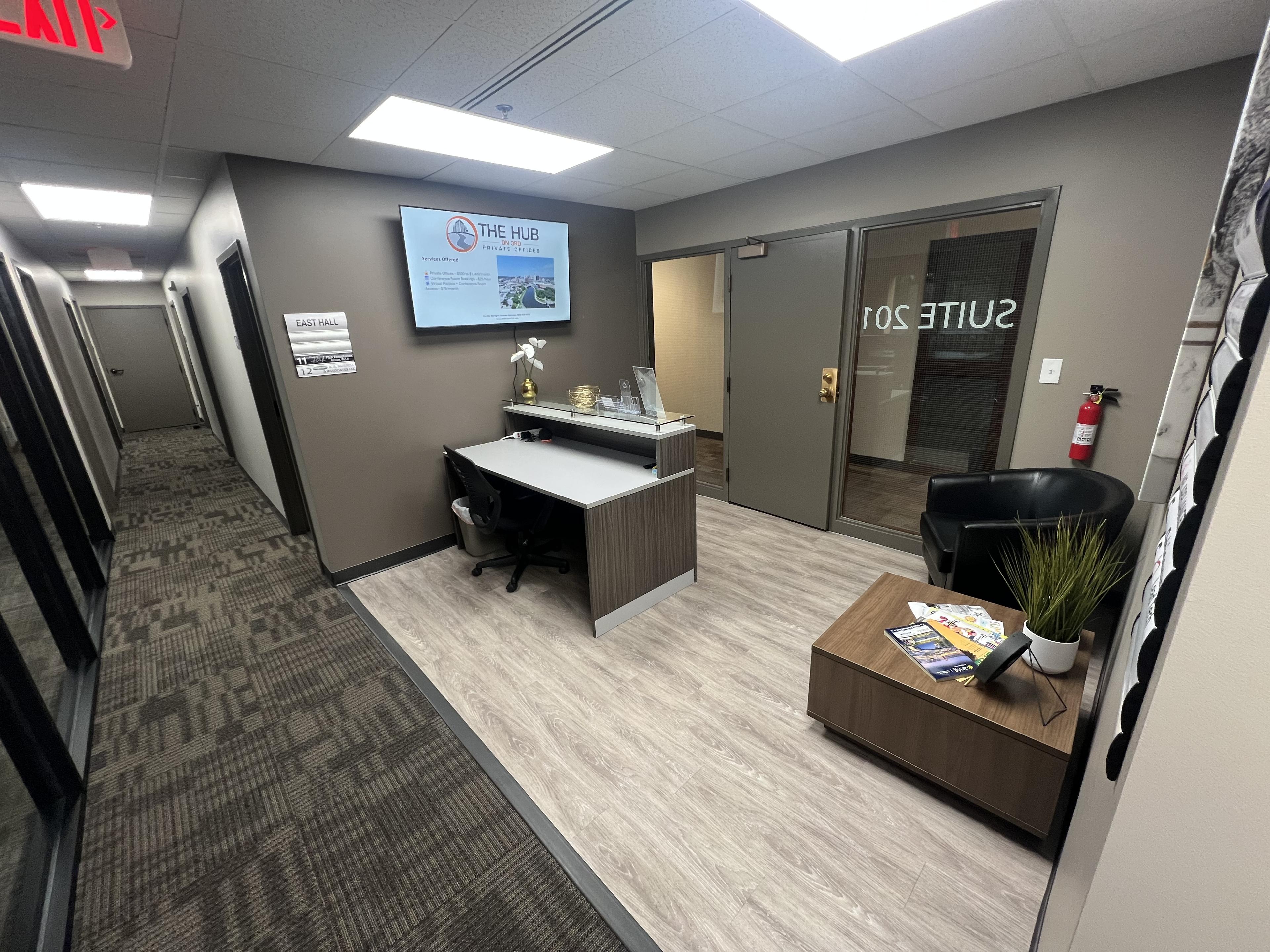 Reception area with tenant directory screen, glass-walled conference room visible behind the front desk