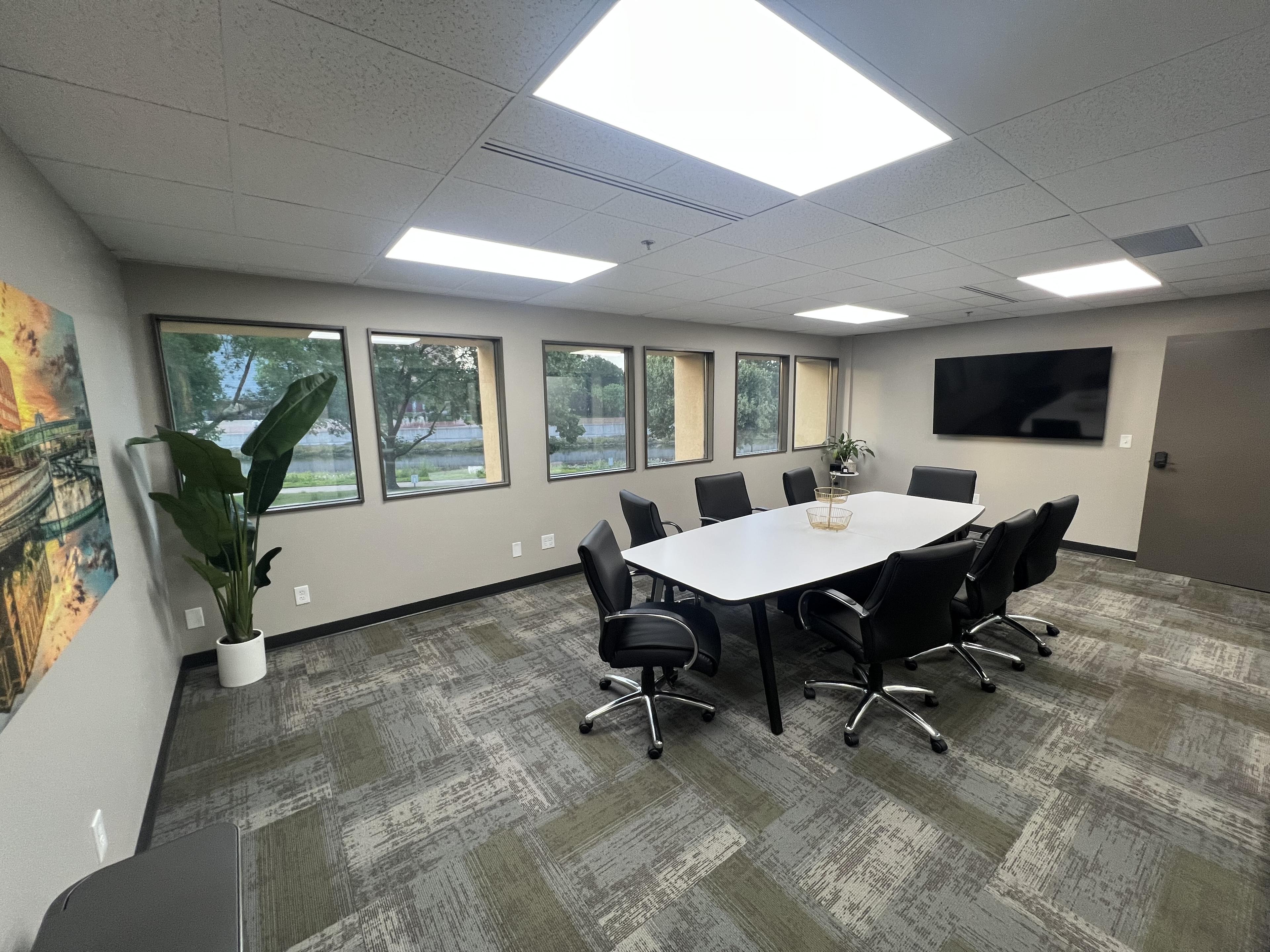 Conference room with a wall of windows overlooking the riverwalk, large display screen, and seating for eight